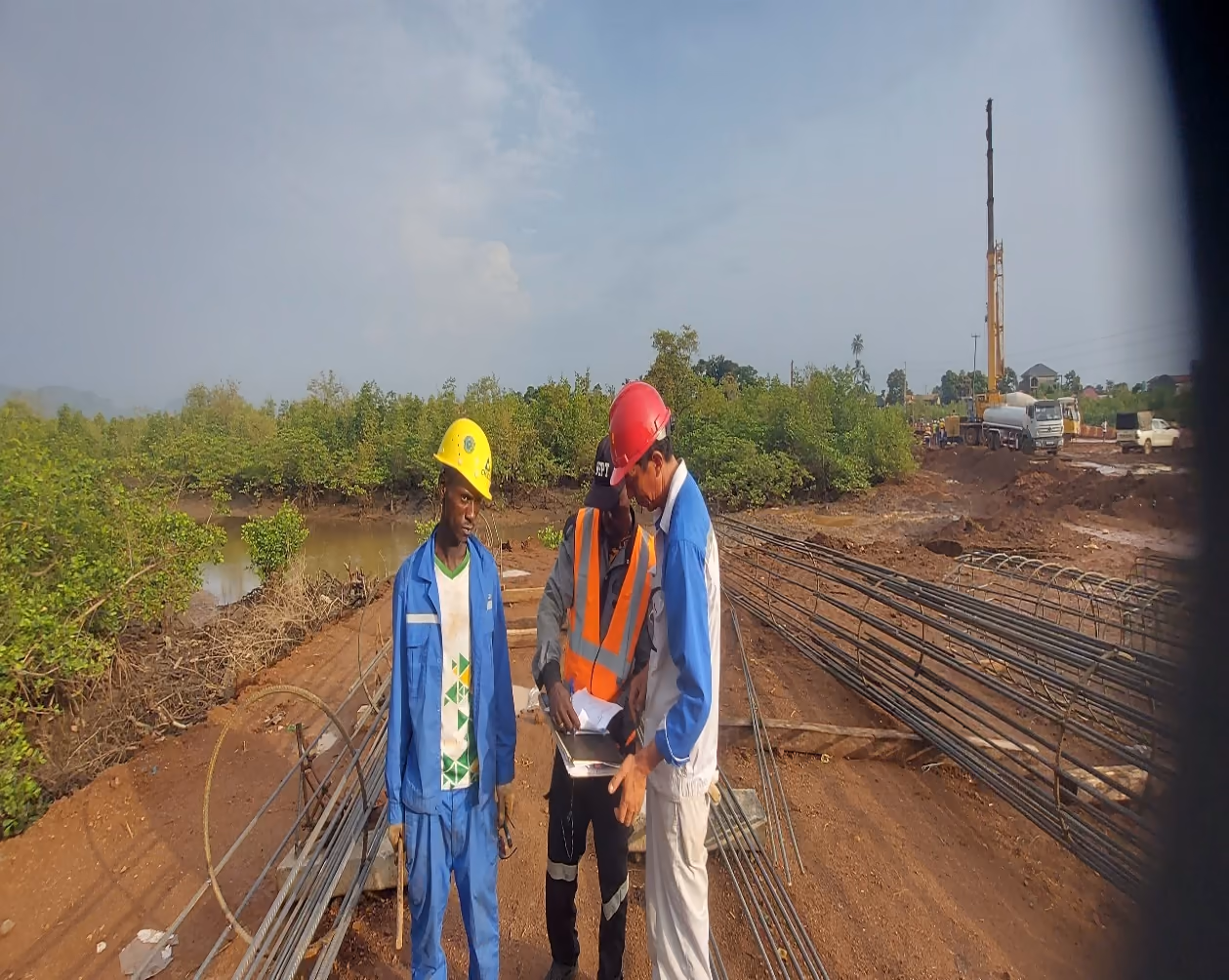 Chantier de construction de pont avec armatures et intervenants casqués